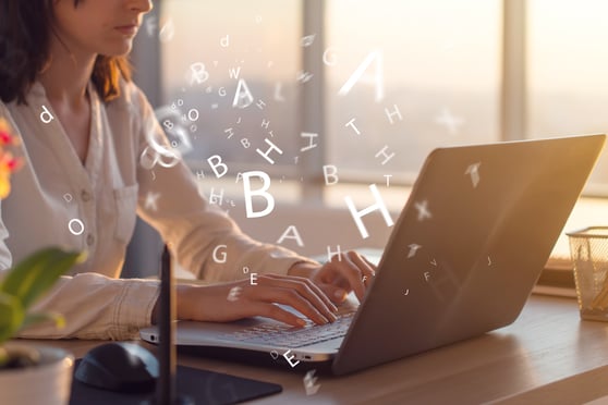 Woman sitting at her laptop, with letter flying around it.