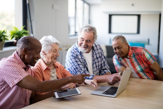 Elderly people sitting around a laptop.