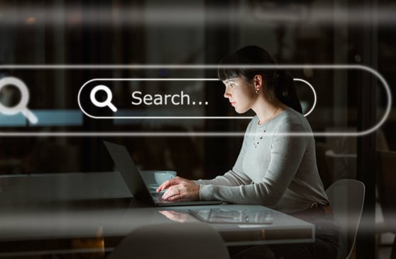 Woman in a dark office in front of a laptop, with a search bar overlaid over her face