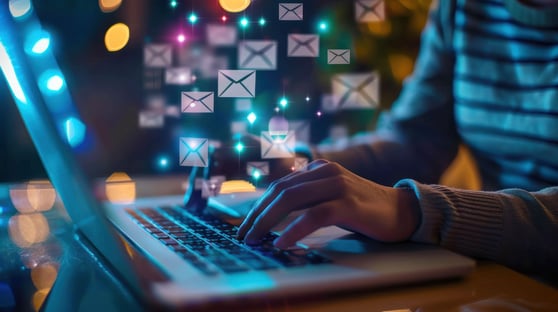 Hands at a laptop with flying email icons around it.