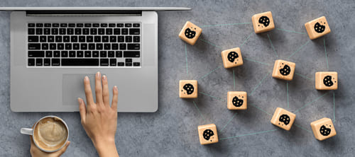 Laptop on a grey desk, with square wooden blocks on the right with pictures of cookies.